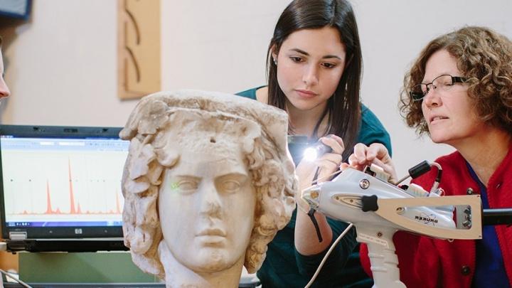 澳门金沙线上赌博官网 professor and her student examine an ancient sculpted bust.